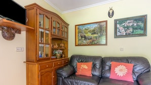 A living room with a leather sofa, wooden cabinet, and two framed paintings on the wall.