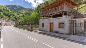 A two-story building with a balcony, a paved road in front, and a mountainous backdrop.