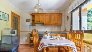 A kitchen with wooden cabinets, a stove, and a dining table set for breakfast.