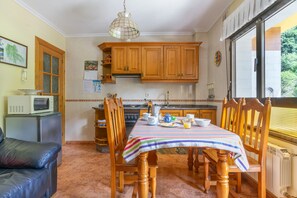 A kitchen with wooden cabinets, a stove, and a dining table set for breakfast.