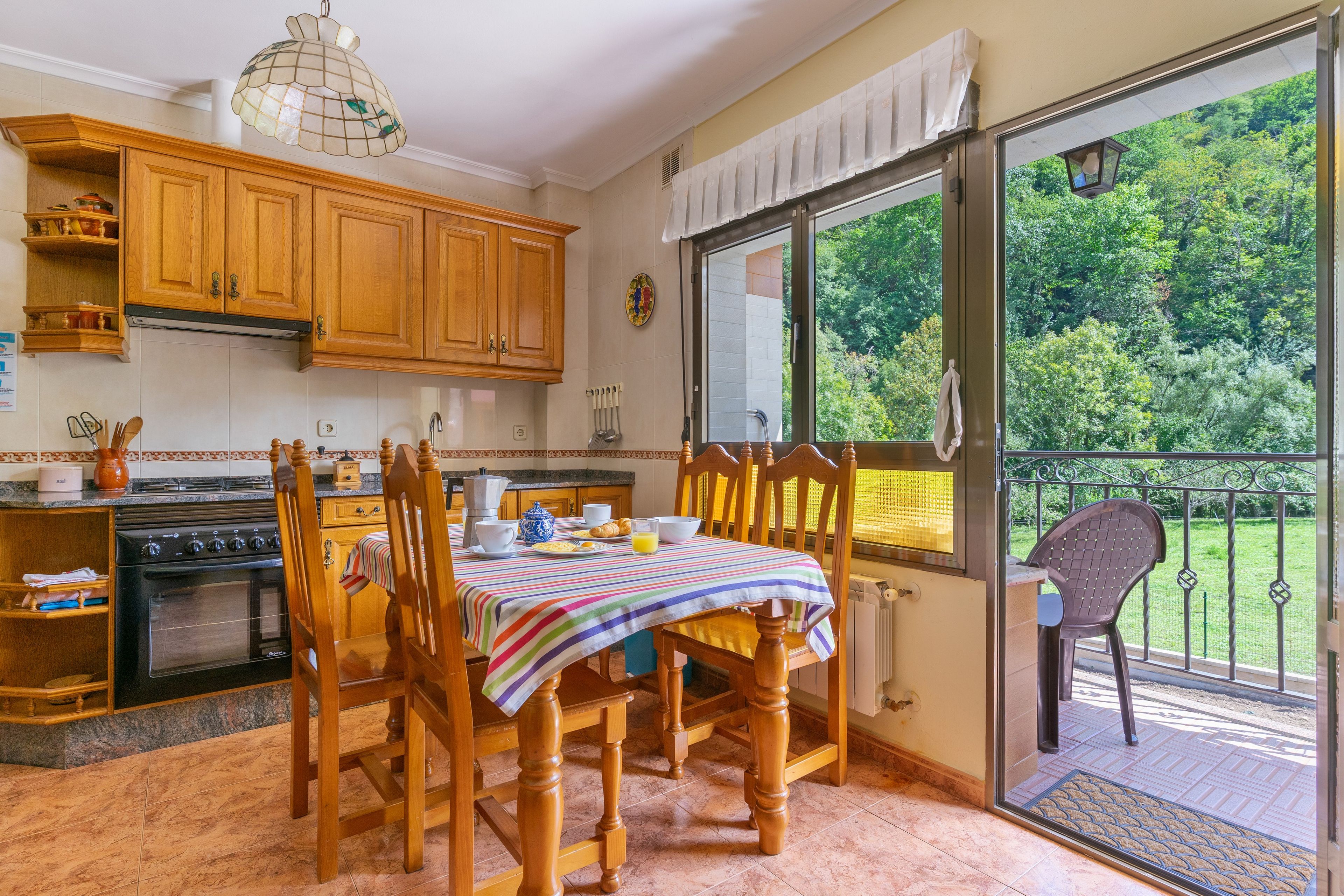 Une cuisine avec des meubles de rangement en bois, une cuisinière et une table à manger avec des chaises.