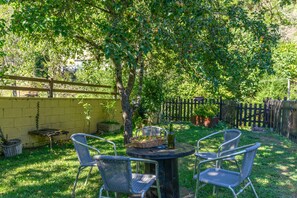A patio with a round table and four chairs, surrounded by a yellow wall and a wooden fence. - Apartment 'La Veiga 1' (La Riera)