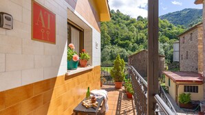 Un balcon avec une table, des chaises et des plantes en pot.