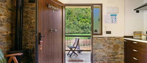 Puerta de madera con la leyenda 'La Vega III' que da a un espacio al aire libre con vistas a la vegetación.
