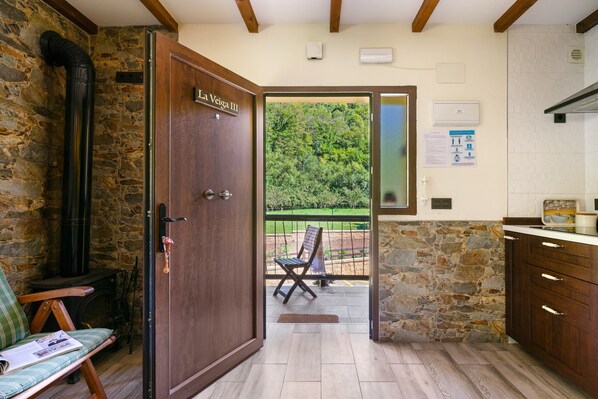 A wooden door labeled 'La Vega III' leading to an outdoor seating area with a view of greenery.