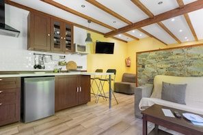 Una cocina con armarios de madera, un microondas integrado y una zona de comedor con pared de piedra.