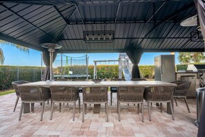Eine Terrasse im Freien mit Tisch, Stühlen, einem Grill und Blick auf die Landschaft.