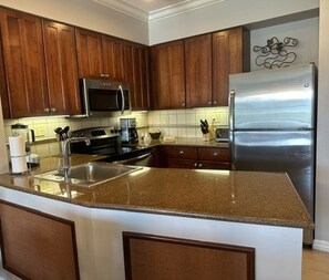 A kitchen with wooden cabinets, stainless steel appliances, and a granite countertop.