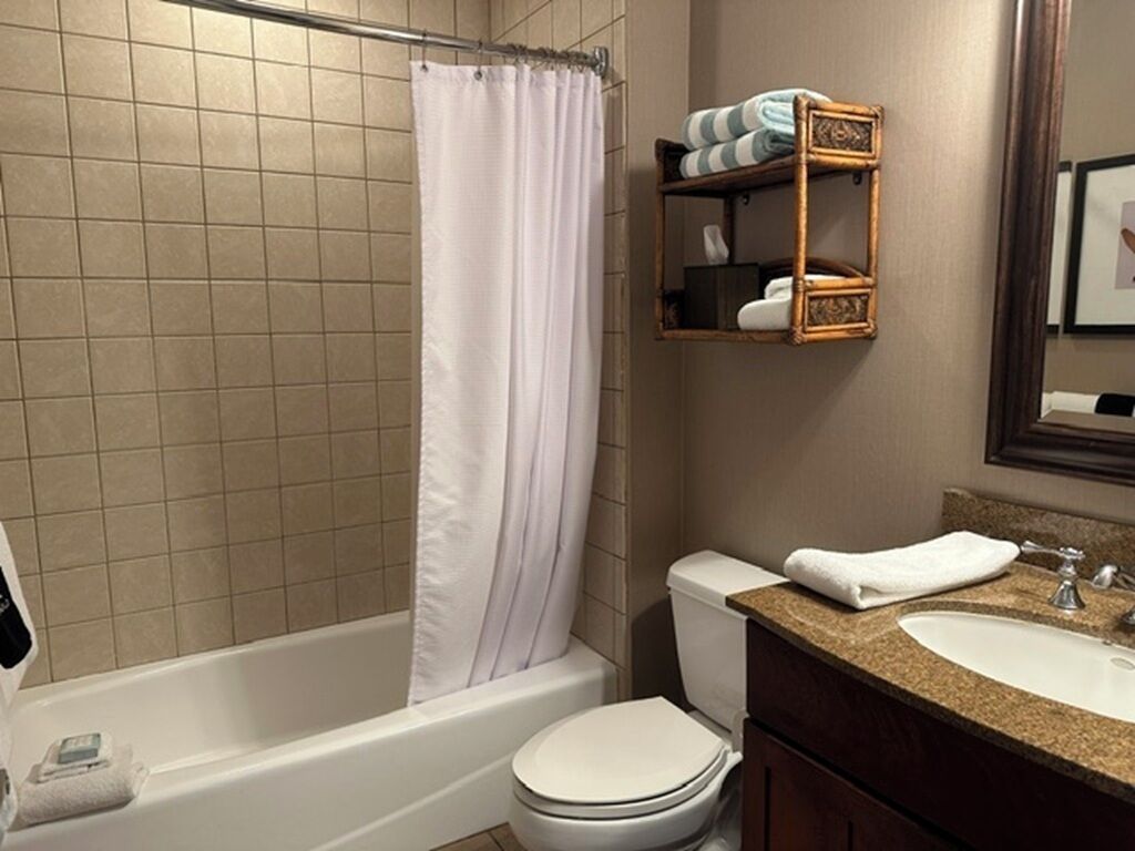 A bathroom with a bathtub, toilet, and a vanity with a sink.