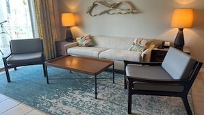 Een woonkamer met een bank, twee fauteuils, een salontafel en twee lampen.