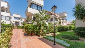 Un quartier résidentiel caractérisé par des allées pavées de tuiles en terre cuite, une végétation luxuriante et des immeubles à plusieurs étages dotés de balcons.