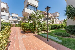 A residential area with terracotta-tiled walkways, lush greenery, and multi-story buildings with balconies. - Sun & Beach Apartment in Torremolinos, just 150m from the beach (Torremolinos)
