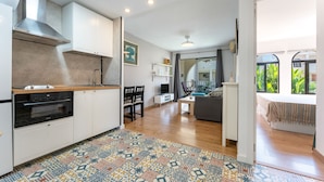 Une cuisine moderne avec des meubles blancs, un four encastré et un tapis à motifs.