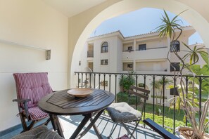 A balcony with a round table, striped chair, and potted plant. - Sun & Beach Apartment in Torremolinos, just 150m from the beach (Torremolinos)