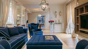 A living room with a sofa, ottoman, and a chair, a chandelier, and a television. - Villa Cesara - Casa del Sole (Vabriga)