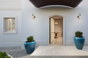 A modern entrance with a curved ceiling, two large potted plants, and a doorway leading to a room with a chandelier. - Villa Cesara - Casa del Sole (Vabriga)
