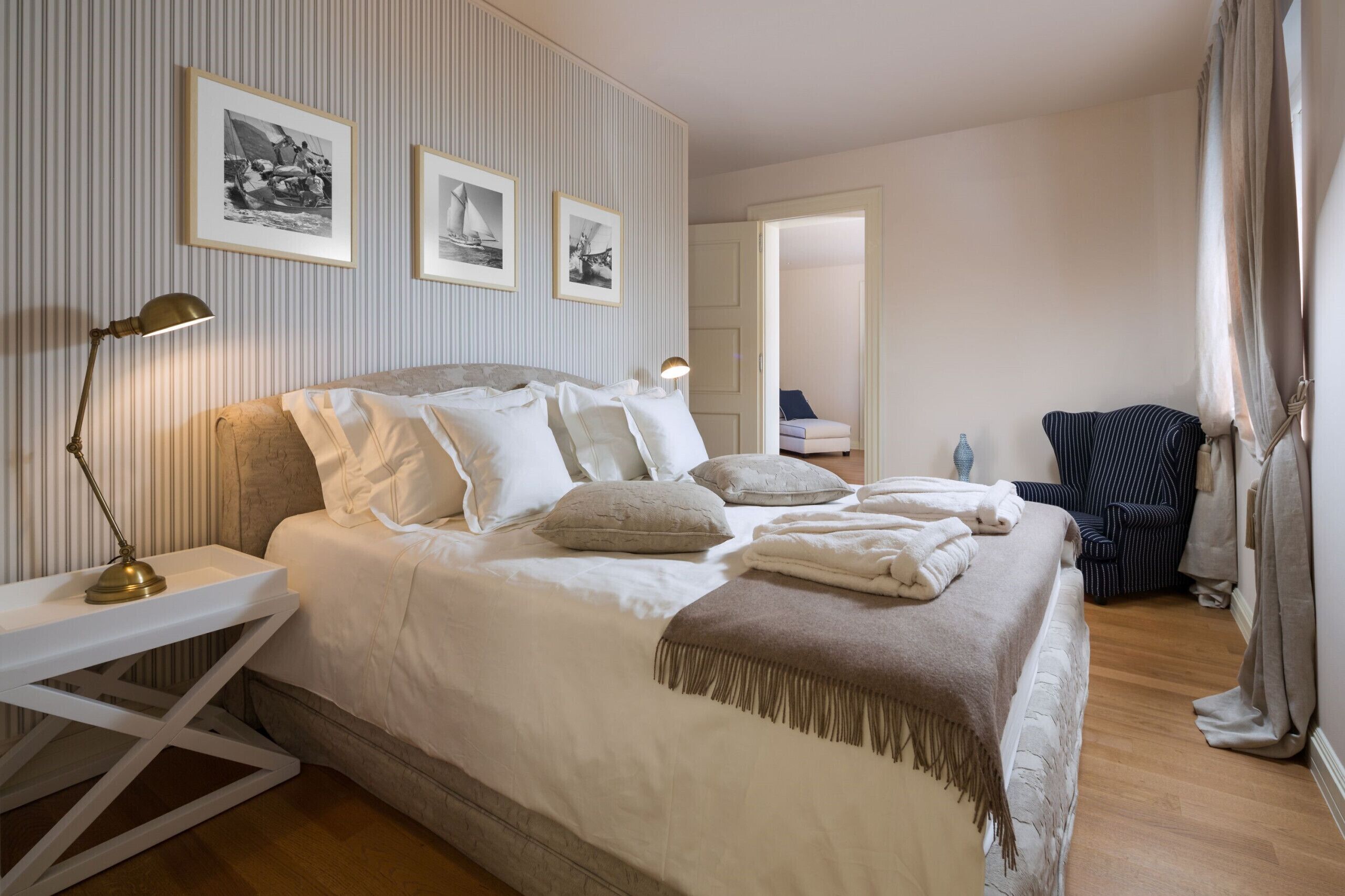 Ein ordentlich eingerichtetes Schlafzimmer mit Bett, Nachttischen, einer Lampe und gerahmten Bildern an der Wand.