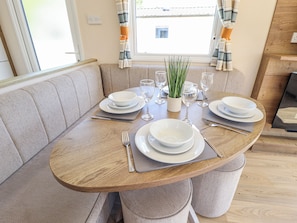 Comedor con una mesa redonda de madera dispuesta para cuatro personas, rodeado de asientos acolchados.