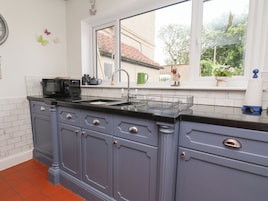 Una cocina con encimera negra, un lavabo y una ventana con vistas al exterior.