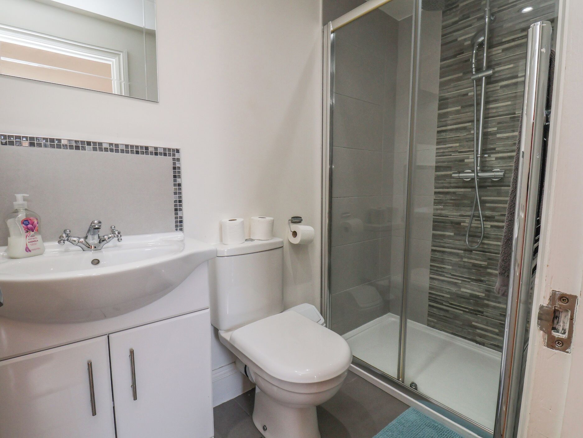 Un baño con lavamanos blanco, inodoro y cabina de ducha de vidrio.