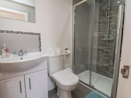 Un baño con lavamanos blanco, inodoro y cabina de ducha de vidrio.