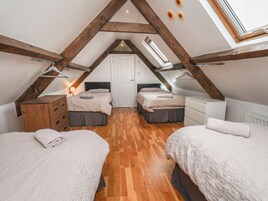 Un dormitorio con dos camas, vigas de madera, un tragaluz y una puerta blanca.