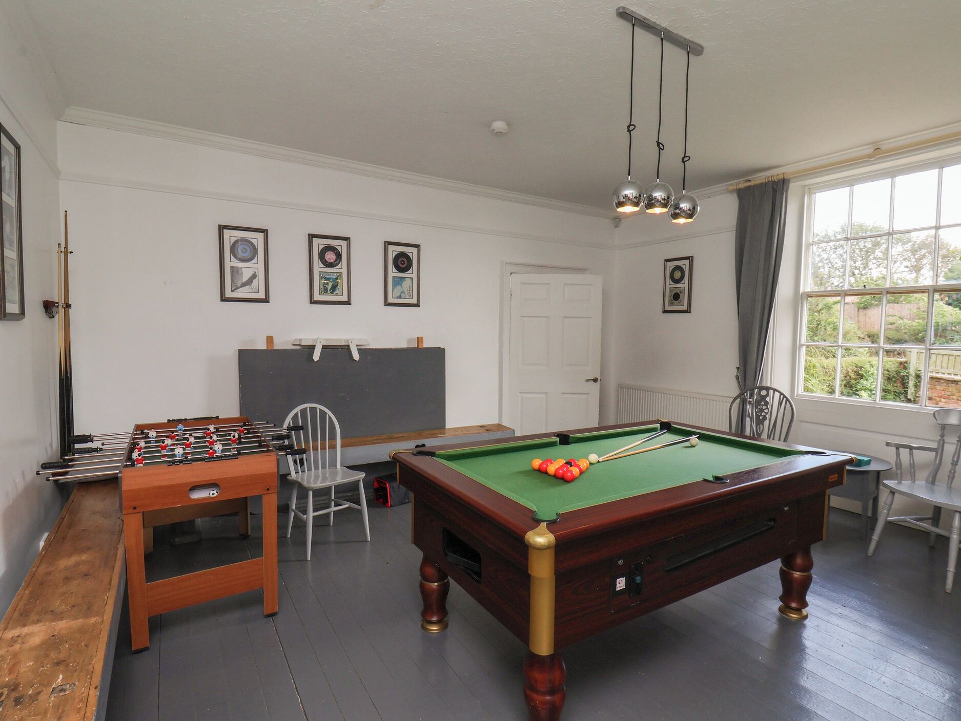 Una habitación con mesa de billar, mesa de fútbolín y equipo de billar.
