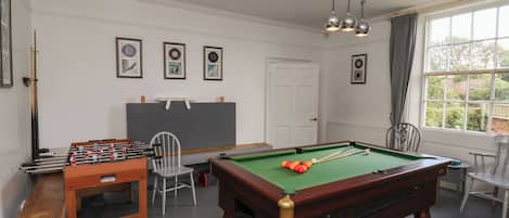 A room with a pool table, foosball table, and billiards equipment.