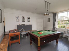 Una habitación con mesa de billar, mesa de fútbolín y equipo de billar.