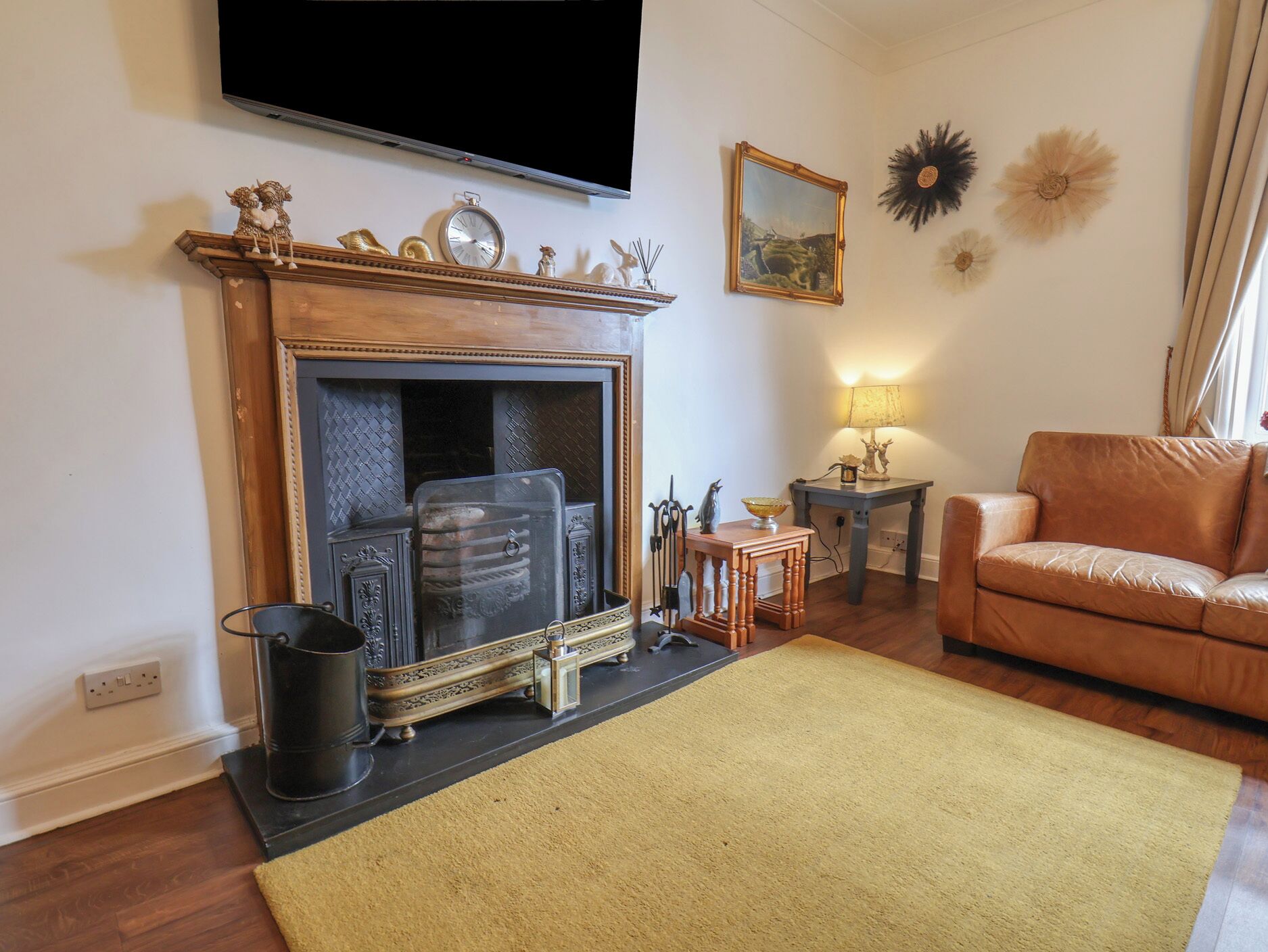 A living room with a fireplace, a sofa, a television mounted on the wall, and decorative items.