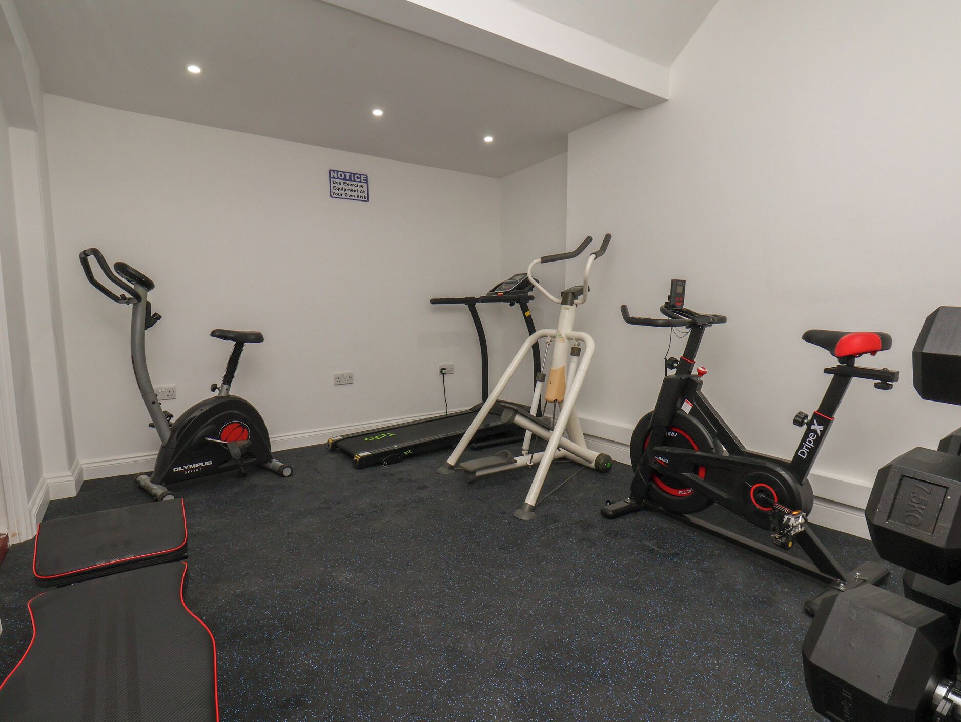 A gym with exercise equipment including a stationary bike, elliptical, and treadmill.