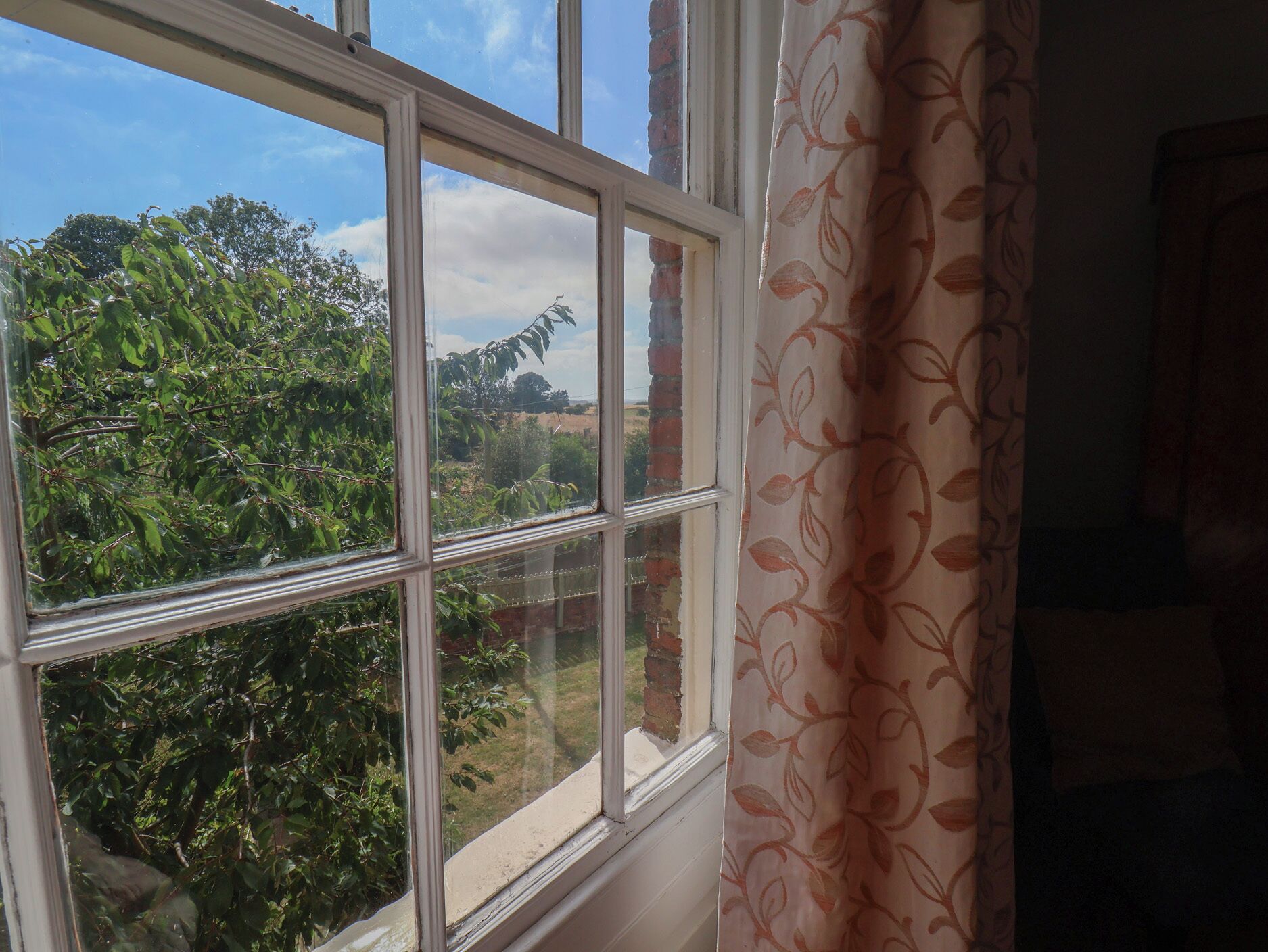 Una ventana con vista a árboles y cielo despejado.