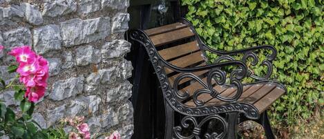 A stone wall, a bench, and a hedge.