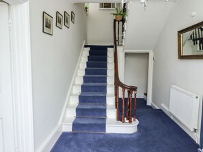 A staircase with blue carpet, white walls, and a wooden handrail. - Reighton House (Filey)