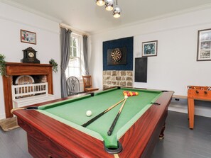 Una sala de billar con mesa de pool, dardos y fútbol de mesa.