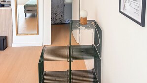Ein modernes Zimmer mit einem Bett, einer kleinen Küchenzeile, einem Badezimmer und einem gerahmten Bild an der Wand.