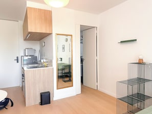 Une cuisine compacte équipée d’un four à micro-ondes, d’un petit réfrigérateur et d’un meuble en bois.