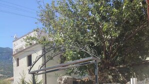 Un mur de pierre, un portail en métal et un bâtiment à la façade blanche.