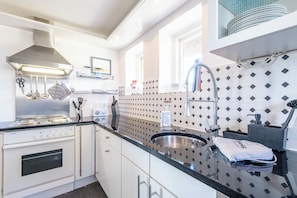 Une cuisine moderne équipée d’une cuisinière en acier inoxydable, d’un évier et d’une fenêtre située au-dessus du plan de travail.