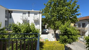 Un edificio residencial con balcones, un árbol y un cielo azul despejado.