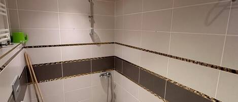 Un baño pequeño con azulejos, que incluye un inodoro, ducha y techo de madera.