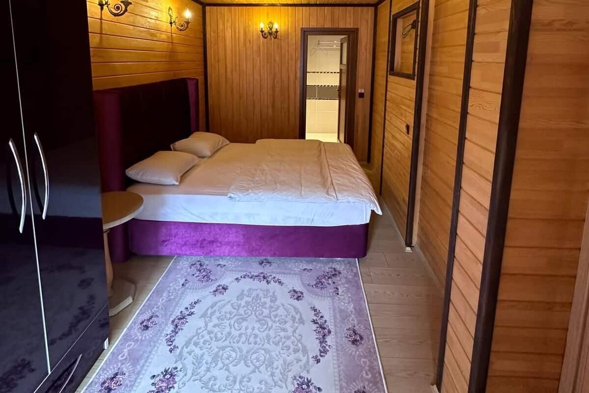 A bedroom with a bed, a wardrobe, a mirror, and a door leading to another room.