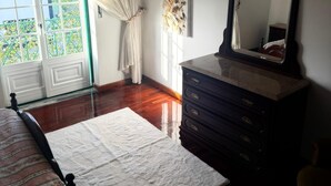 Une chambre à coucher avec un lit, une commode, un miroir et une fenêtre avec des rideaux.