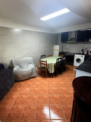 A compact living space with a dining area, kitchenette, and a sofa. - Vio's Home (Serra d' El-Rei)