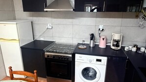 Une cuisine compacte équipée d’une cuisinière, d’un four, d’un lave-linge et d’une machine à café.