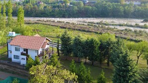 Una casa con techo rojo, rodeada de vegetación y un río.