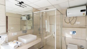 Un baño moderno con ducha envuelta en cristal, lavamanos blanco y secador de pelo en la encimera.