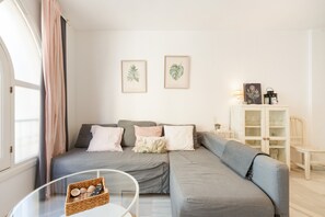 A modern living room with a grey sectional sofa, a glass coffee table, and a white cabinet with glass doors.