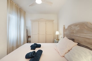 Et hotelværelse med en seng, et klædeskab, et natbord med lampe og en loftsvifte.