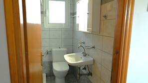 Ein kleines Badezimmer mit Toilette, Waschbecken und einem Fenster über der Toilette.